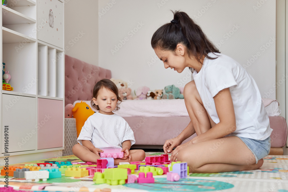 cute baby girl and her loving mom playing with toy bricks in the children room, having fun together cute baby girl and her loving mom playing with toy bricks in the children room, having fun together