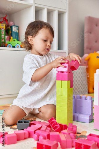 cute baby girl playing with colorful toys bricks at home