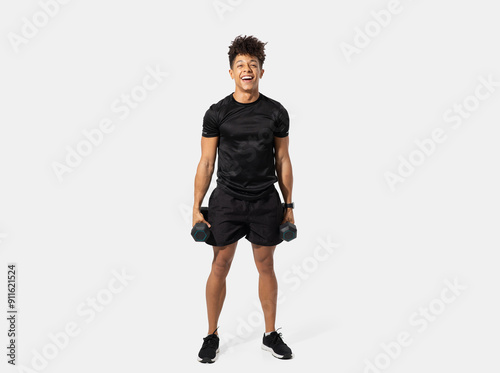 A young adult stands confidently with a pair of dumbbells in each hand, showcasing an energetic and positive attitude. The guy is dressed in athletic gear, ready to engage in a strength training