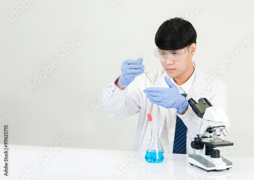 Portrait asian man student scientist wearing a doctor gown in the lab looking hand at chemist. caused by mixing reagents in scientific research laboratories with test tubes and microscope on the table