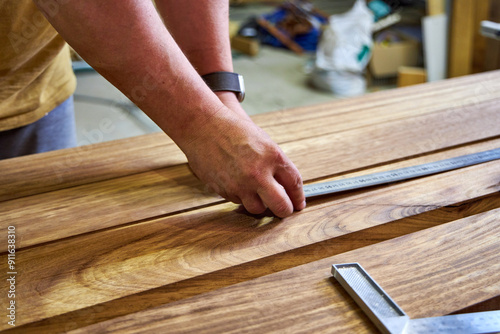 a man in a home carpentry workshop measuring boards close-up of hands