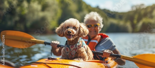 Senior woman kayaking with happy poodle dog
