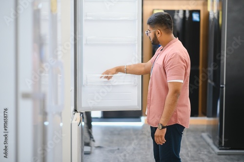 Smart modern indian male customer choosing large fridges in domestic appliances section