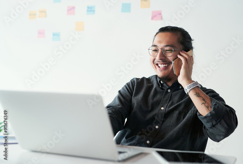 Smile, laptop and phone call with asian man in office, planning and search for startup in creative agency. Solution, web developer and calling with mobile for business, talking or listening to client