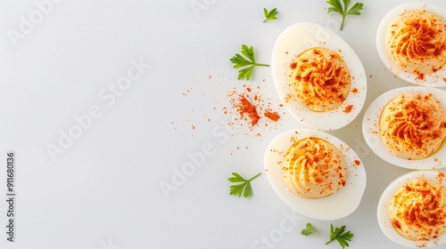 Deviled eggs with paprika and parsley on a white plate on a white background. Minimalistic flat lay style with space for text. Ideal for banners, marketing materials, backgrounds, and food-related des photo