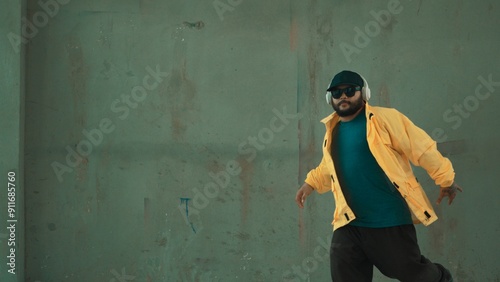 Hipster shows or practicing footstep at street, urban city. Motion shot of young stylish break dancer moving and stretch arm and leg. Outdoor sport 2024. Gray background. Hip hop fashion. Hiphop. photo