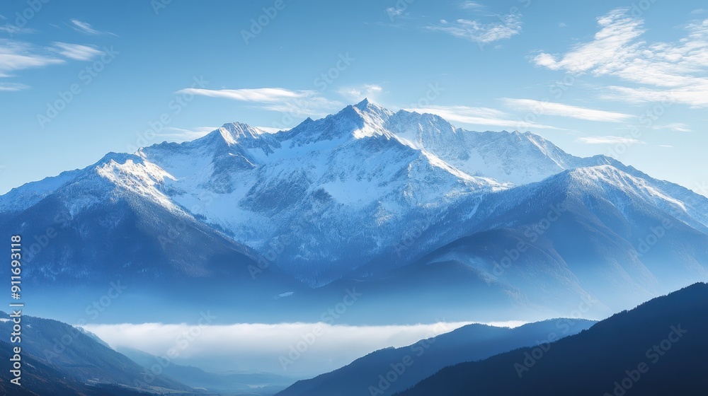 Obraz premium Majestic snow-covered mountain range with blue sky and clouds, creating a serene and breathtaking landscape view.