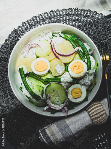 Salad healthy bowl with  egg, potatoes, onion, cucumber, green beans, and dressing.