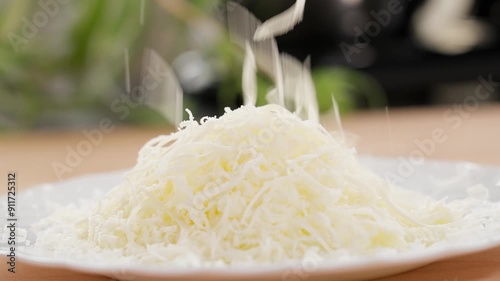Macro. Cheese is grated on a fine grater into a plate in a heap. Parmesan, Gouda, hard cheese. Grated cheese, cheese filling for baking, cheese with pasta. Close-up, front view