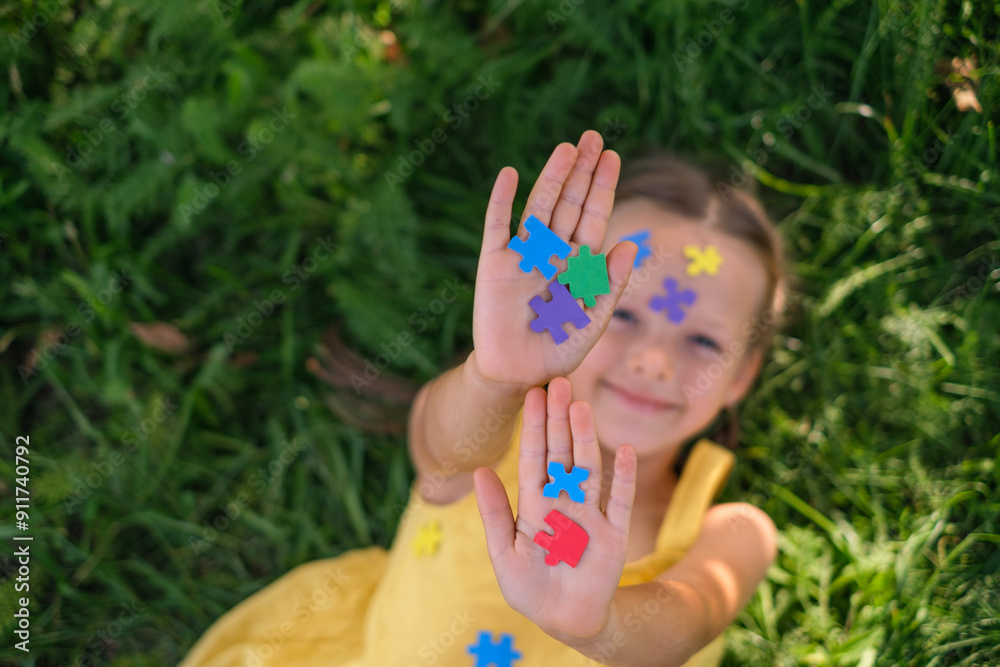 A beautiful sweet smiling happy girl holds pieces of colored puzzles in her palms. World Autism Awareness Day A beautiful sweet smiling happy girl holds pieces of colored puzzles in her palms. World Autism Awareness Day