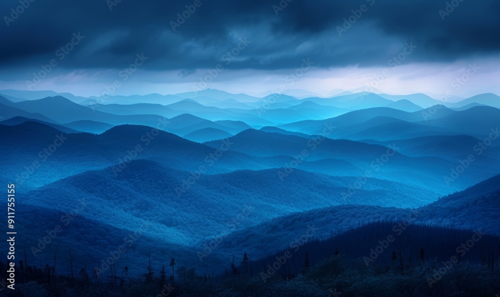 Fototapeta premium Dramatic stormy sky over layered blue mountains at nightfall