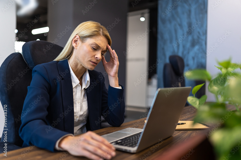 Caucasian woman employee sitting at desk working on laptop in office Caucasian woman employee sitting at desk working on laptop in office