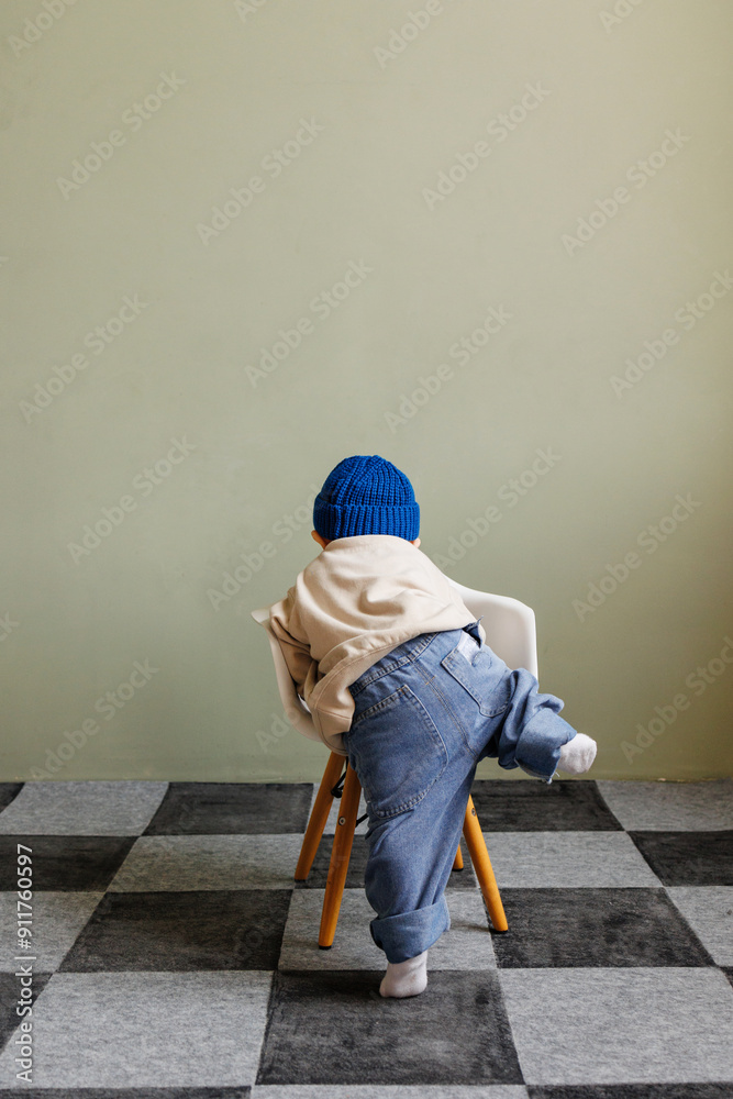 A little boy climbs up on a chair.