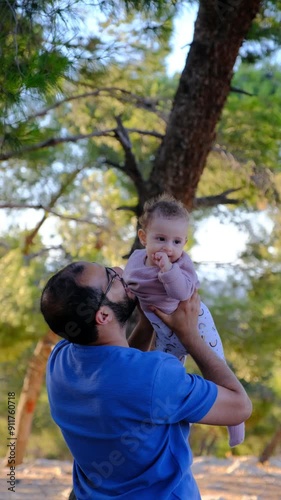 A father holding his baby girl and raising her to the sky, making her smile and having a great time