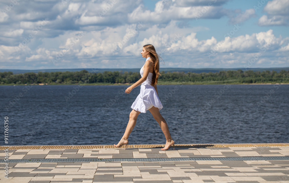Young beautiful woman in a summer dress walking along the embankment Young beautiful woman in a summer dress walking along the embankment