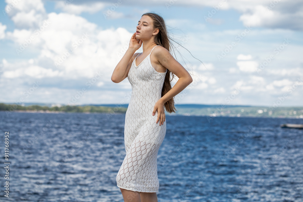Portrait of a young beautiful blonde girl in a white summer dress with open shoulders Portrait of a young beautiful blonde girl in a white summer dress with open shoulders