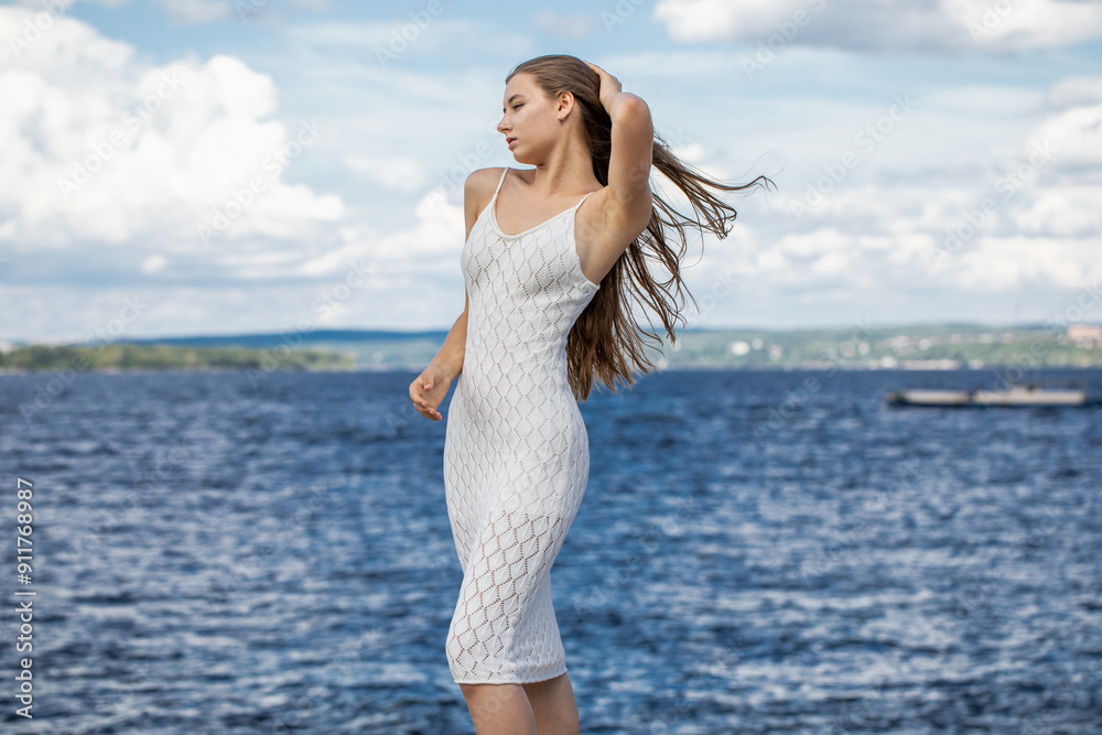 Portrait of a young beautiful blonde girl in a white summer dress with open shoulders Portrait of a young beautiful blonde girl in a white summer dress with open shoulders