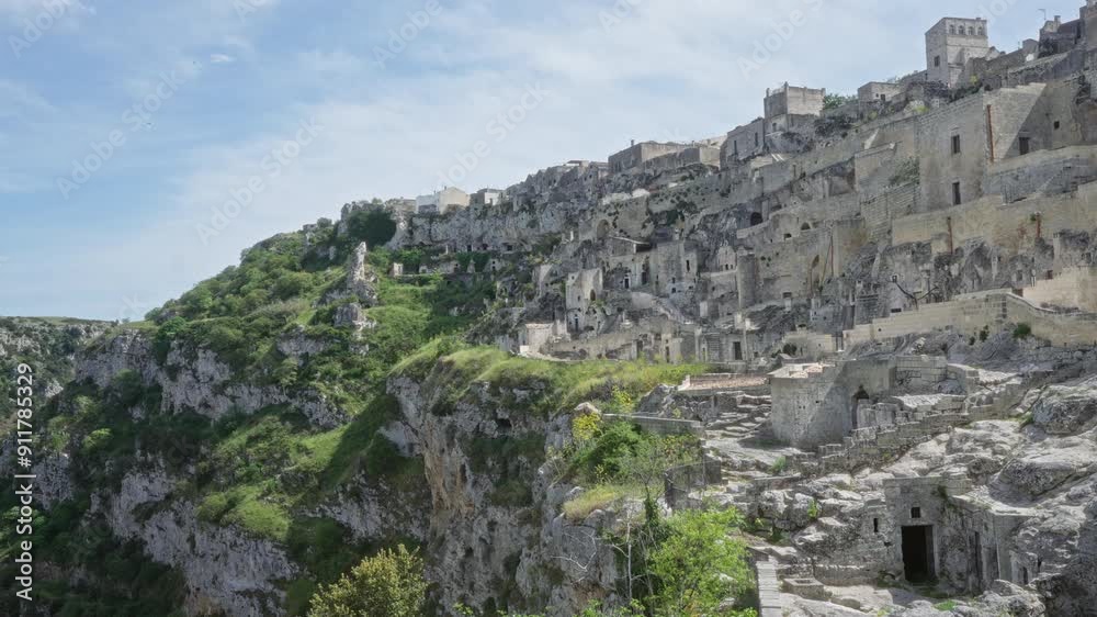 Panoramic view of the historic cliffside town of matera in basilicata, italy, showcasing ancient stone buildings and lush greenery under a clear blue sky. Panoramic view of the historic cliffside town of matera in basilicata, italy, showcasing ancient stone buildings and lush greenery under a clear blue sky.