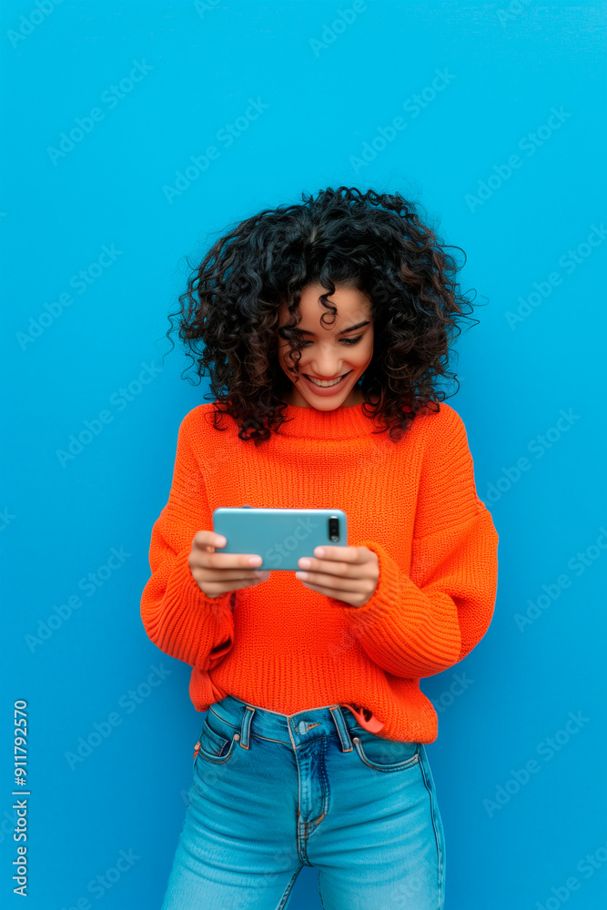 A happy, smiling young African-American curly-haired woman shopping online with her cell phone, sitting on a couch at home. A happy, smiling young African-American curly-haired woman shopping online with her cell phone, sitting on a couch at home.