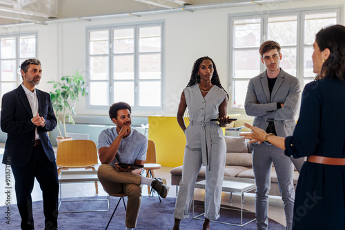 Business people listening to female team leader at office