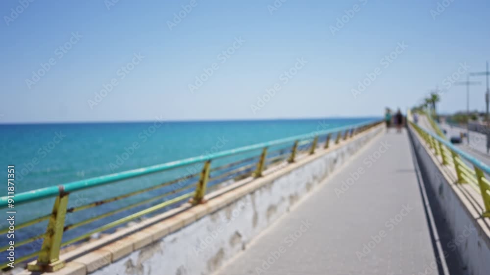Long walkway with railing leading to the horizon's edge of the clear blue sea under a sunny sky with defocused view Long walkway with railing leading to the horizon's edge of the clear blue sea under a sunny sky with defocused view