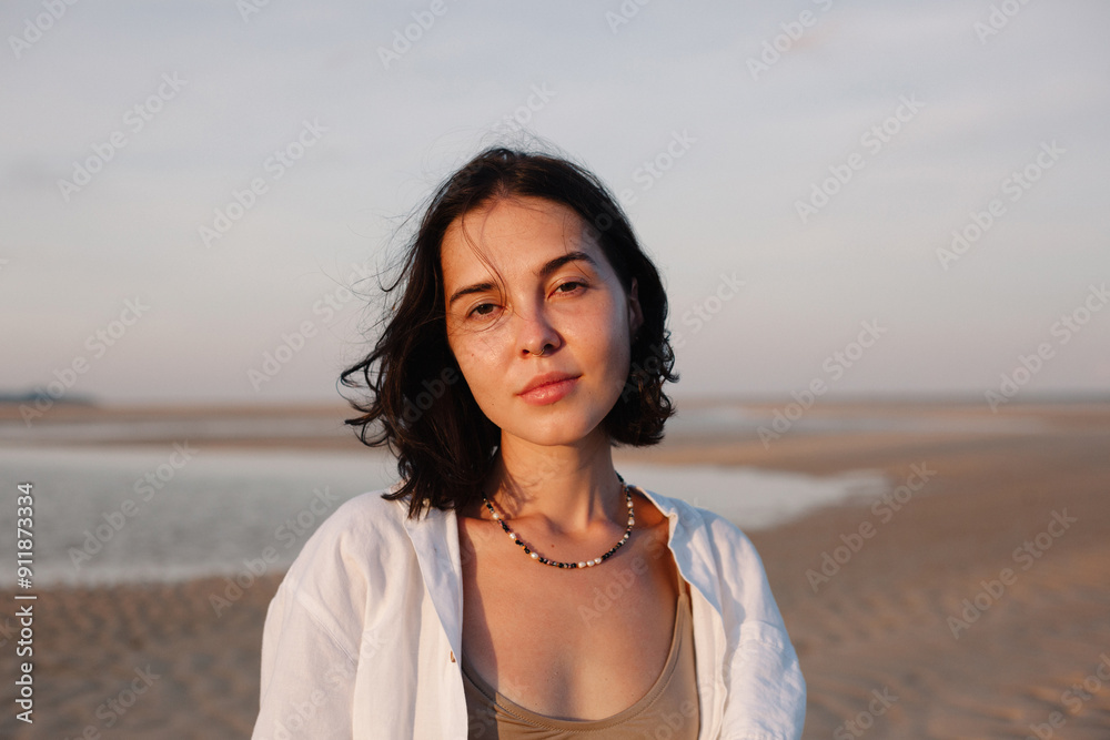 Smiling tanned brunette woman standing on sandy beach Smiling tanned brunette woman standing on sandy beach