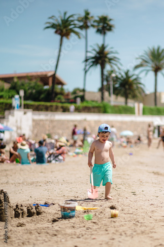 Child plays on beach with shovel photo