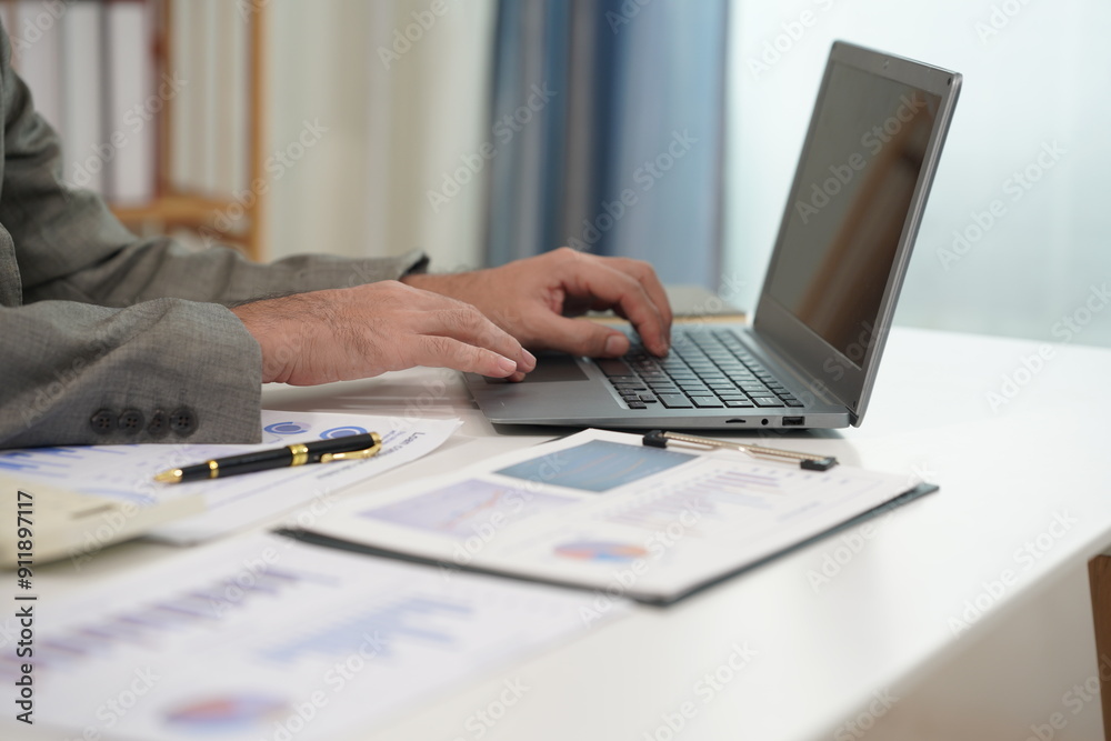 Businessman using calculator with laptop computer, budget and loan documents in office. Company auditor calculating budget with calculator on desk in office. Close up. Businessman using calculator with laptop computer, budget and loan documents in office. Company auditor calculating budget with calculator on desk in office. Close up.