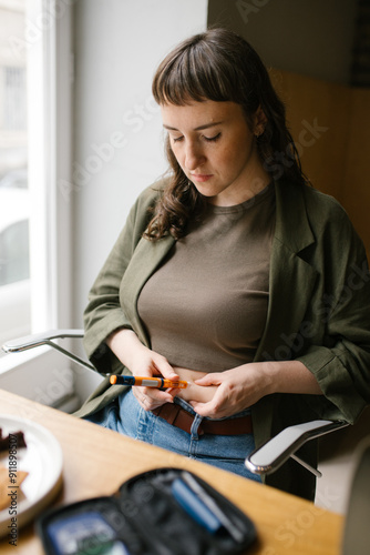 Diabetic woman injecting herself with insulin in cafe photo