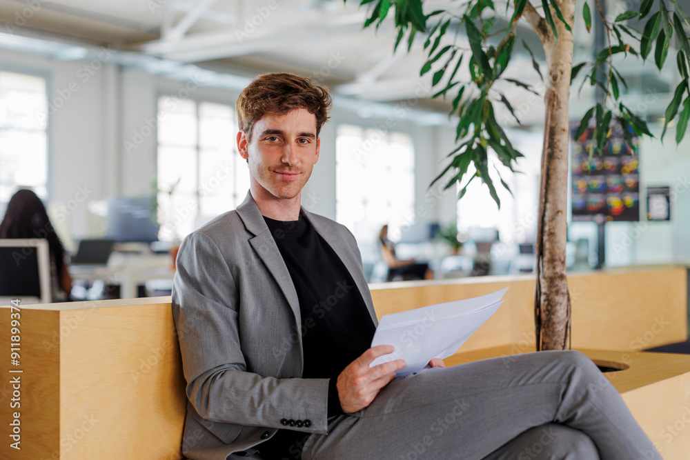 Manager sitting in modern open plan office holding documents Manager sitting in modern open plan office holding documents