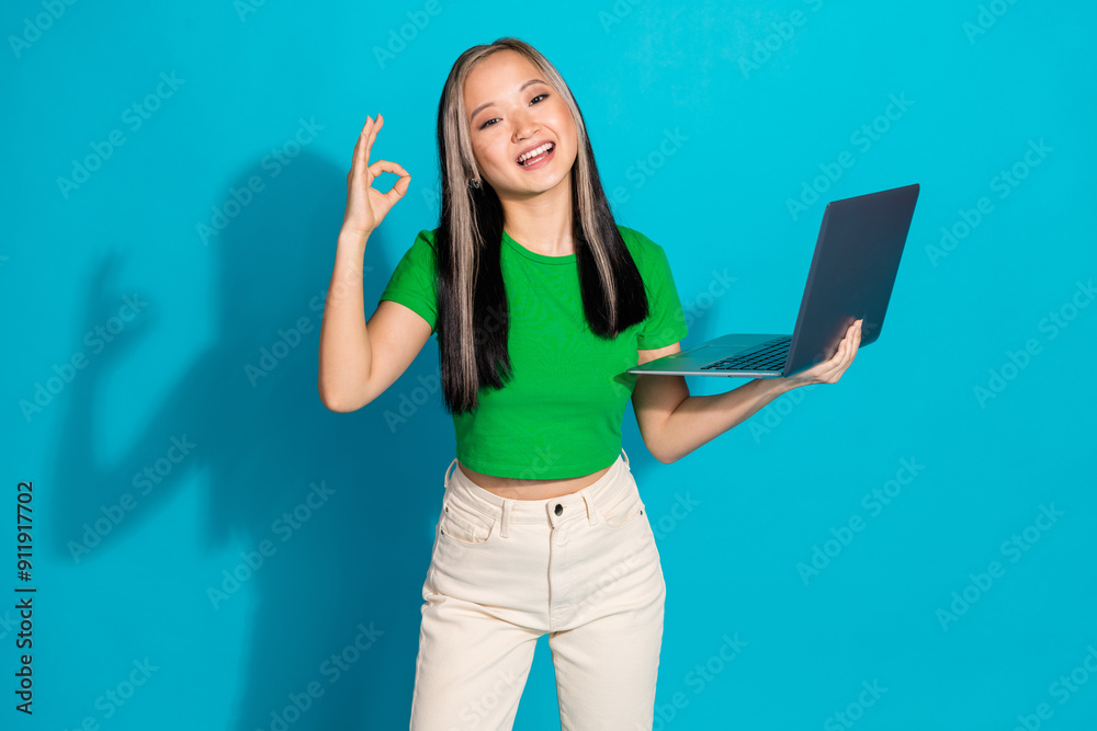 Photo of nice young girl netbook show okay symbol wear green t-shirt isolated on teal color background Photo of nice young girl netbook show okay symbol wear green t-shirt isolated on teal color background