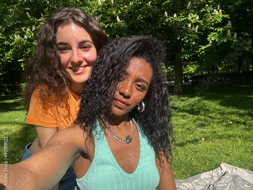 A couple of lesbian women take a selfie with a cell phone in a park