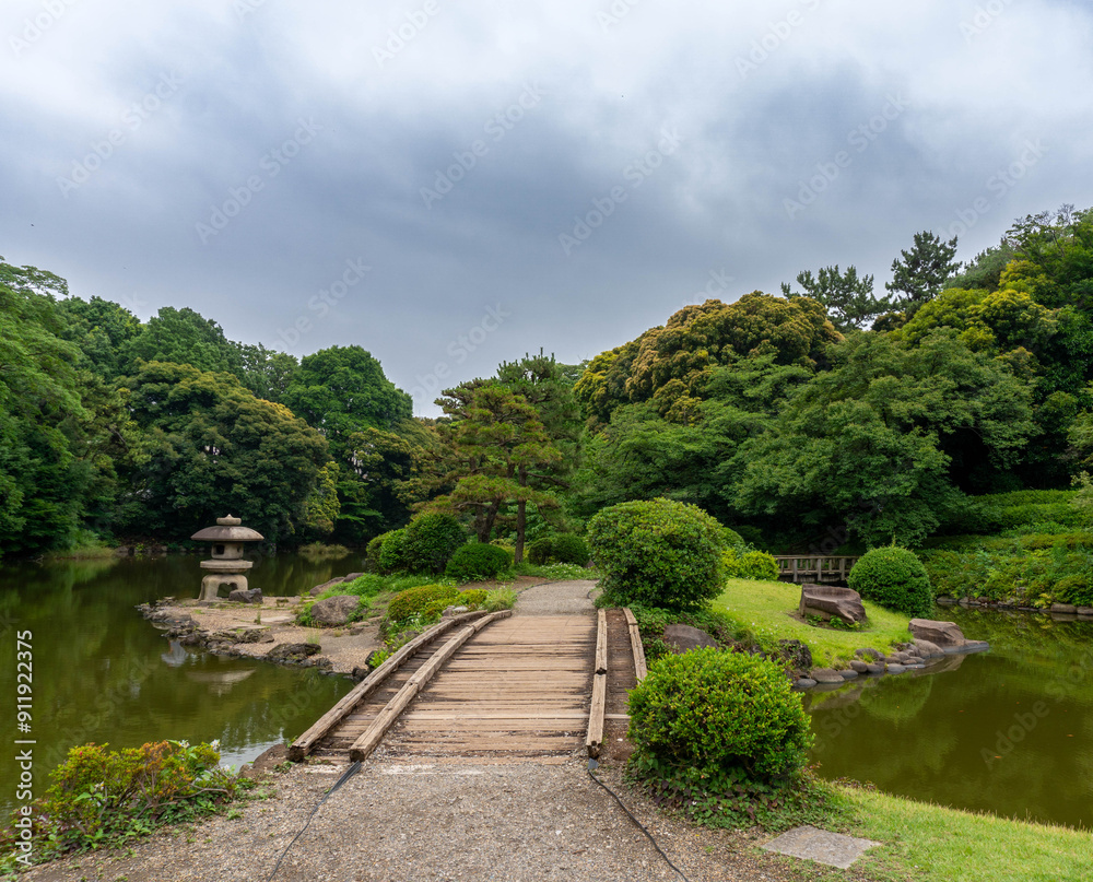 Walkway leading to small island in the middle of a well manicured Japanese garden Walkway leading to small island in the middle of a well manicured Japanese garden