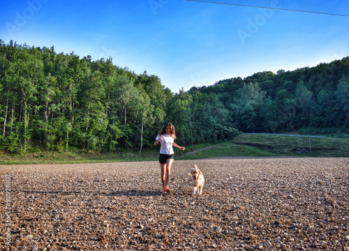 Woman and dog running in field photo