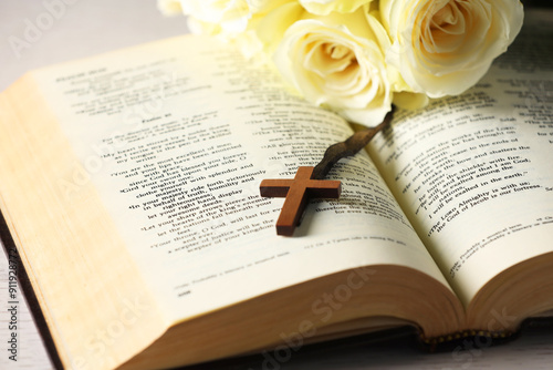 Bible, cross and roses on light table, closeup. Religion of Christianity