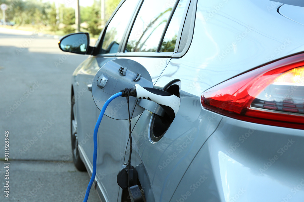 Naklejka premium Charging modern electric car from station outdoors