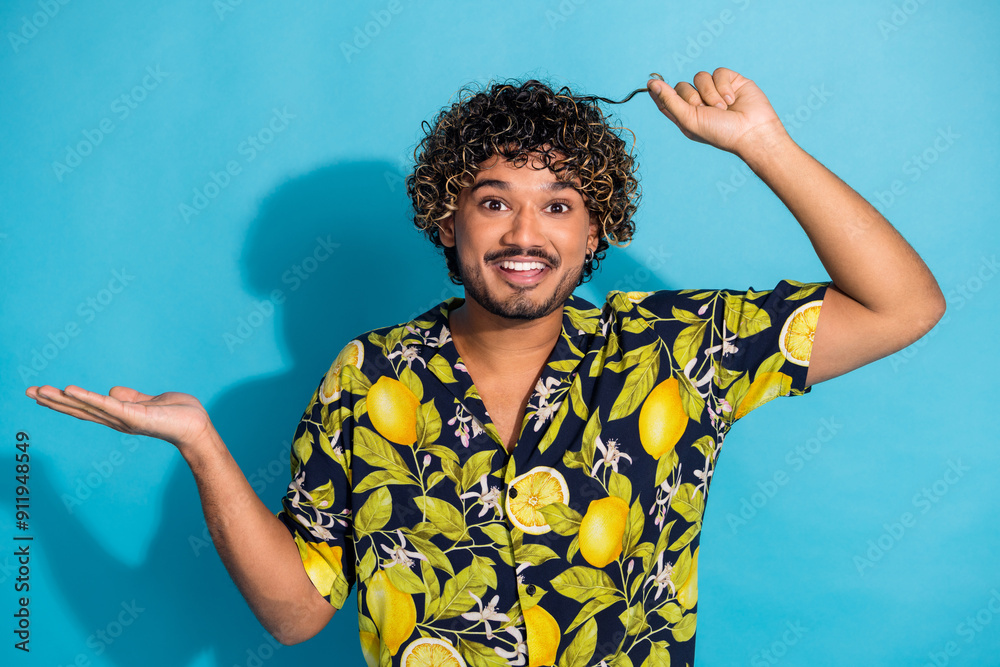 Photo of optimistic guy with beard wavy hairstyle dressed print shirt hold curl palm show empty space isolated on blue color background