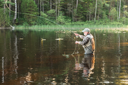 Fisherman Standing in Lake Amidst Scenic Wilderness