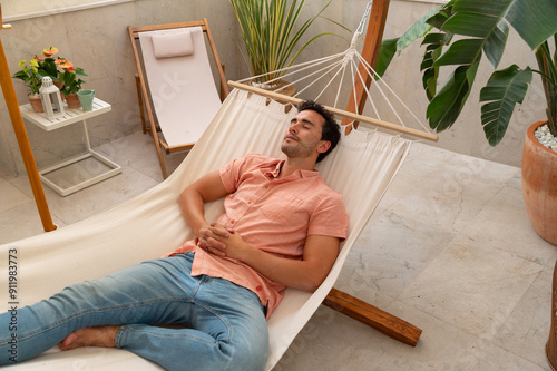 Man relaxing in a hammock in a cozy indoor setting with plants photo