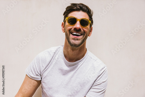 Man wearing sunglasses with a bright smile and casual white t-shirt