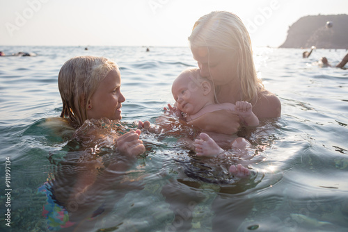 Children with baby swimming in the sea photo