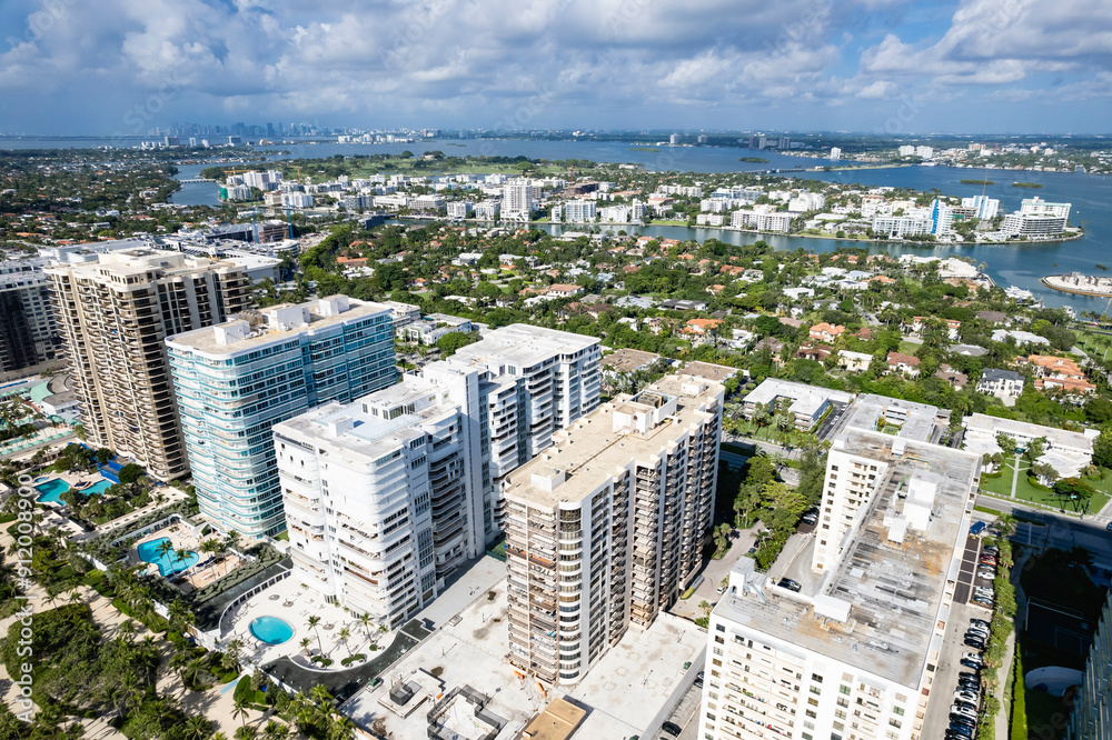 Fototapeta premium Miami Beach, Florida, USA - July 15, 2024: Aerial of Oceanfront condominiums and luxurious mansions at the Bal Harbour neighborhood. Bay Harbor Island, Biscyane Bay, and Miami skyline in background.