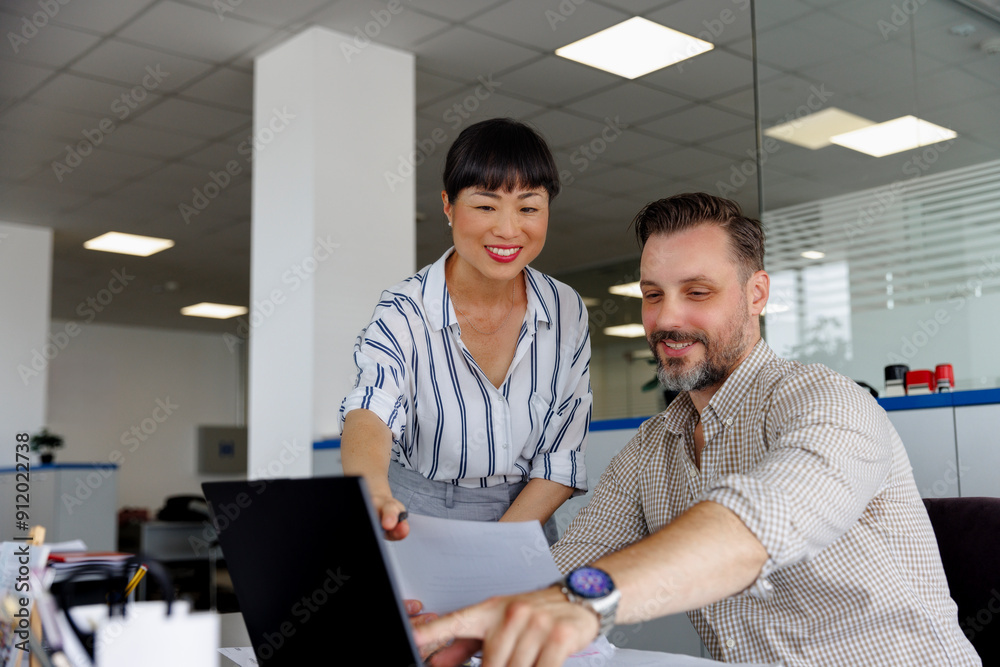 Smiling businessman explaining colleague over laptop Smiling businessman explaining colleague over laptop