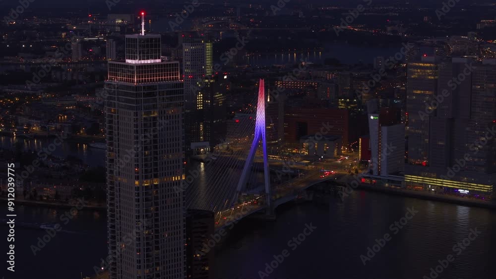 Lvely city lights and bustling nightlife of Rotterdam from above, showcasing the illuminated erasmus bridge and surrounding skyscrapers at night
