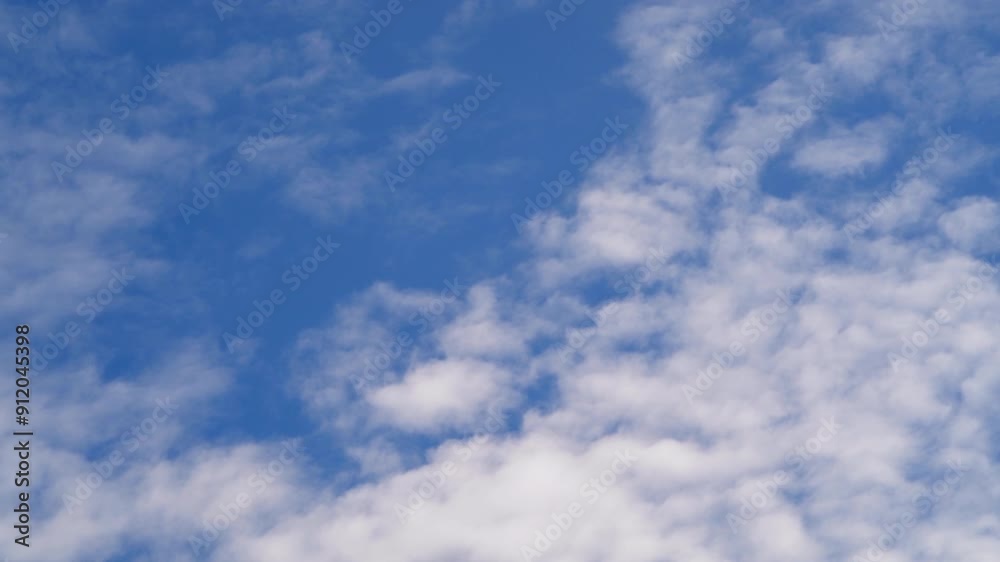 Time-lapse of Altocumulus Fluffy white clouds drift lazily across a vast, clear blue sky Time-lapse of Altocumulus Fluffy white clouds drift lazily across a vast, clear blue sky