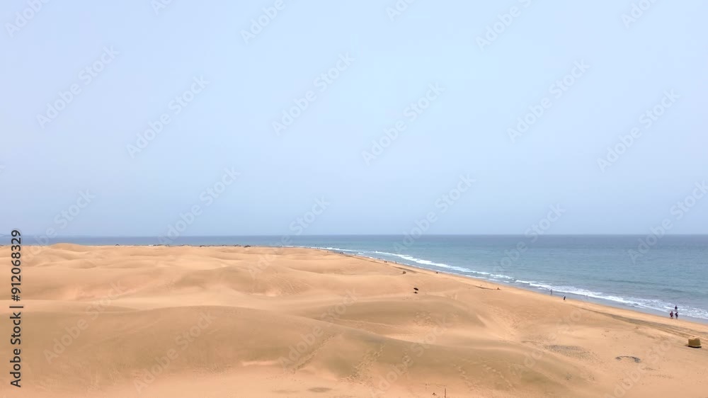 Sand dunes desert against seascape in Maspalomas Gran Canaria deserts near seashore. Aerial drone view of tourists walking thorugh the dunes of Maspalomas in Gran Canaria during a windy day. Sand dunes desert against seascape in Maspalomas Gran Canaria deserts near seashore. Aerial drone view of tourists walking thorugh the dunes of Maspalomas in Gran Canaria during a windy day.