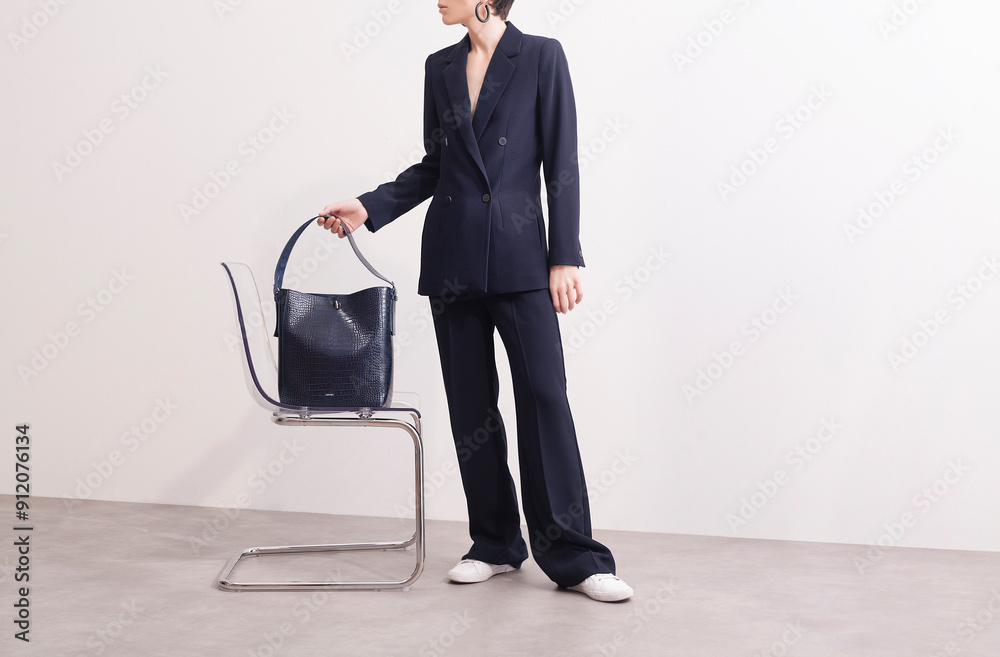 © Ulas&Merve/Stocksy - Fashionable Woman in Suit Holding a Designer Bag © Ulas&Merve/Stocksy - Fashionable Woman in Suit Holding a Designer Bag