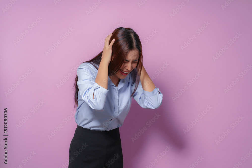 Young asian businesswoman experiencing a painful headache, grimacing in discomfort while holding her head Young asian businesswoman experiencing a painful headache, grimacing in discomfort while holding her head
