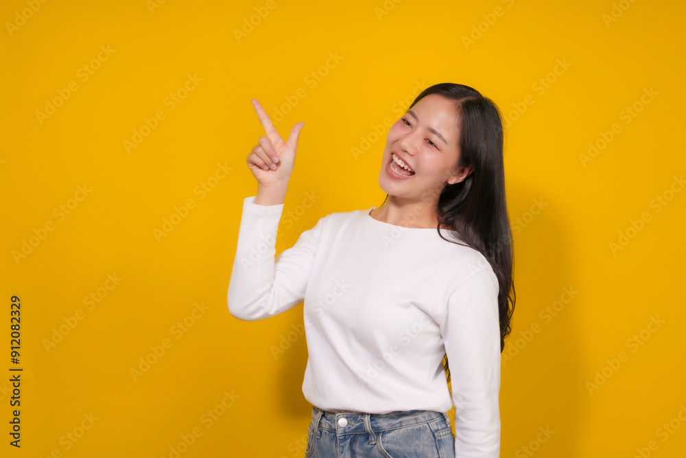 Young woman stands on a bright yellow background, pointing and smiling cheerfully, radiating happiness and positivity, perfect for ads or promotions Young woman stands on a bright yellow background, pointing and smiling cheerfully, radiating happiness and positivity, perfect for ads or promotions
