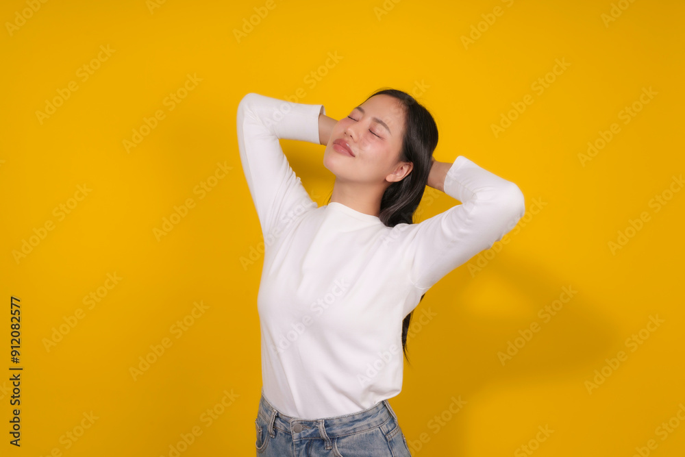 Young woman is enjoying a moment of peace and tranquility with her hands behind her head, her eyes closed and a serene expression on her face Young woman is enjoying a moment of peace and tranquility with her hands behind her head, her eyes closed and a serene expression on her face